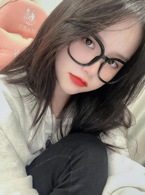 Cô gái tóc dài đeo kính, gương mặt xinh đẹp tự nhiên.
